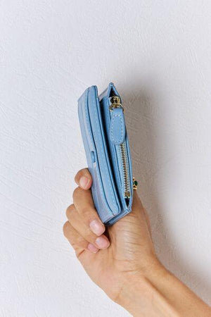 a person holding a small blue purse in their hand