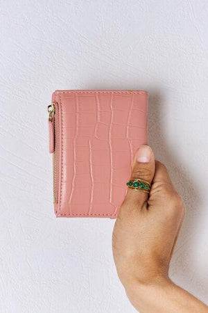a person holding a pink wallet in their hand