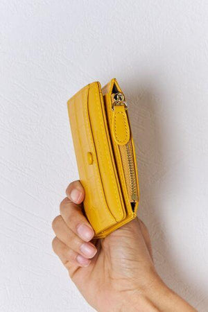 a person holding a yellow purse in their hand