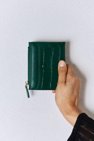 a person holding a green wallet in their hand