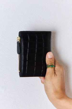 a hand holding a black wallet with a green ring