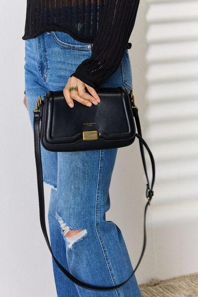 a woman in ripped jeans holding a black purse