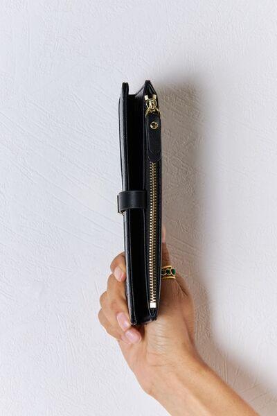 a hand holding a black purse with a gold zipper