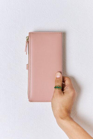a person holding a pink wallet in their hand