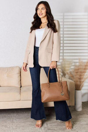 a woman standing in front of a couch holding a brown purse