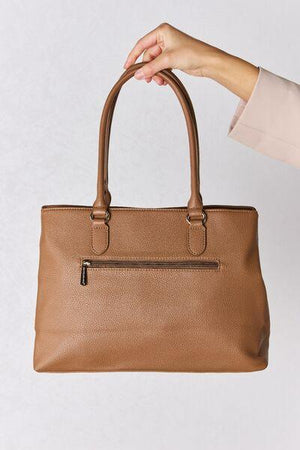 a woman's hand holding a brown purse