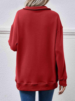 a woman wearing a red sweatshirt and jeans