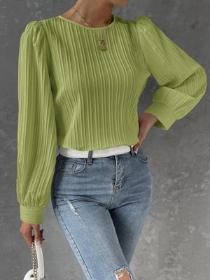 a woman wearing a green sweater and ripped jeans