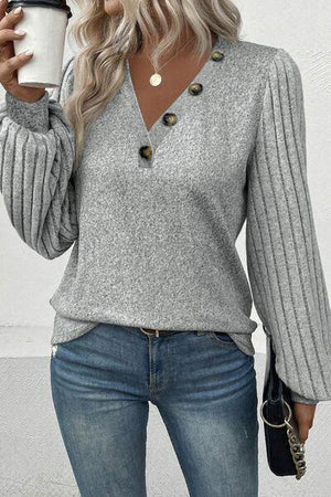 a woman wearing a gray sweater and jeans holding a cup of coffee