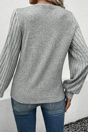 a woman wearing a grey sweater and jeans