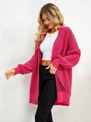 a woman wearing a pink cardigan sweater and black pants