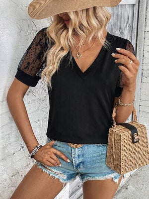 a woman wearing a black top and denim shorts