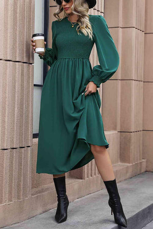 a woman wearing a green dress and black hat