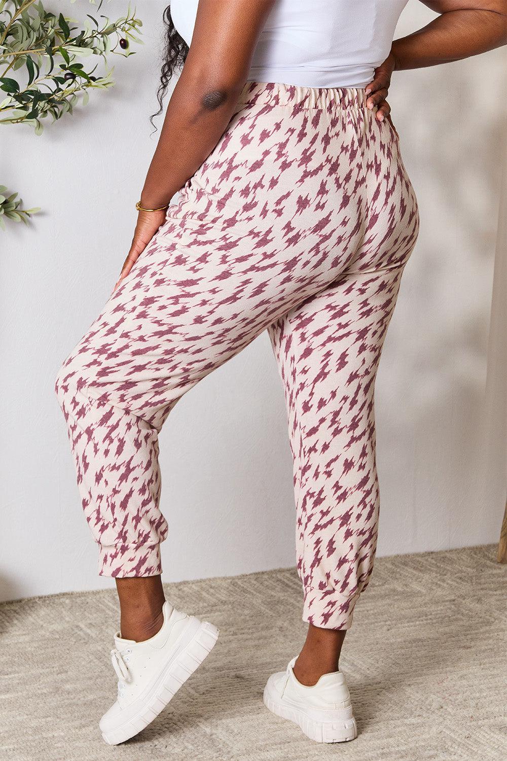 a woman in a white tank top and patterned pants
