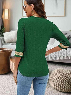 a woman standing in a living room wearing a green top