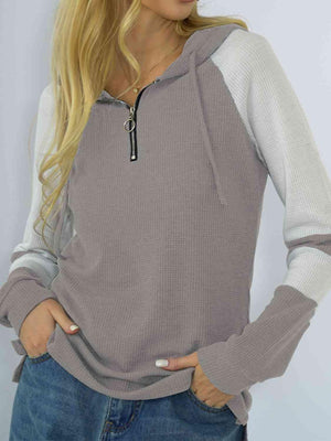 a blonde woman wearing a gray and white hoodie