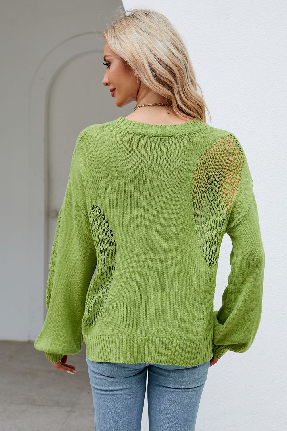 a woman wearing a green sweater and jeans