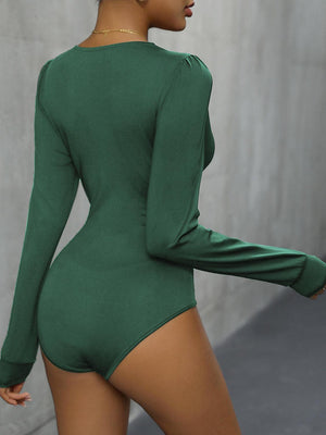 a woman in a green bodysuit posing for the camera