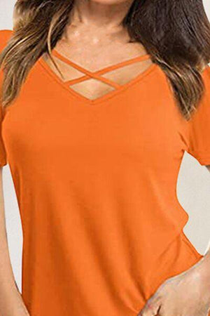 a woman wearing an orange top with a cross back