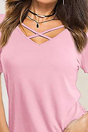 a woman wearing a pink top with a cross cut neckline