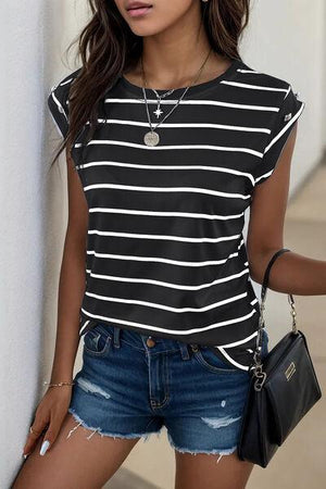 a woman leaning against a wall wearing a black and white striped shirt