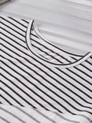 a white and black striped shirt laying on top of a bed