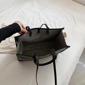 a person holding a black purse on a bed