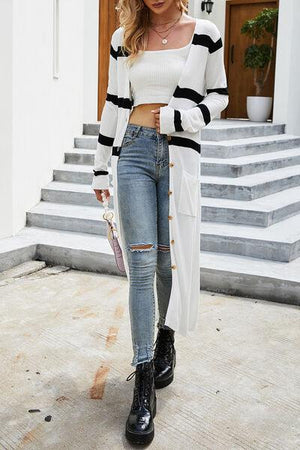 a woman wearing ripped jeans and a white sweater