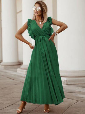 a woman in a green dress standing on a sidewalk