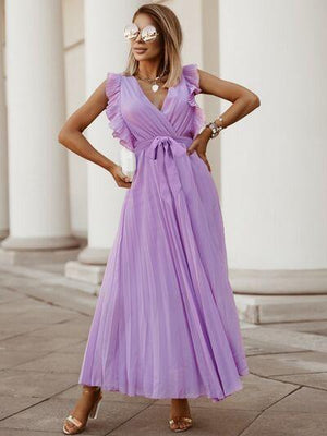 a woman in a purple dress standing on a sidewalk