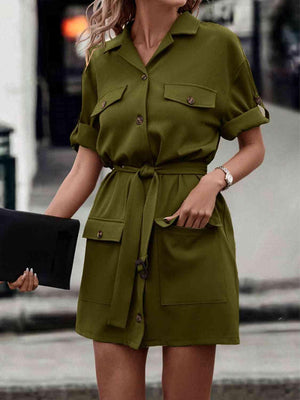 a woman in a green shirt dress is walking down the street