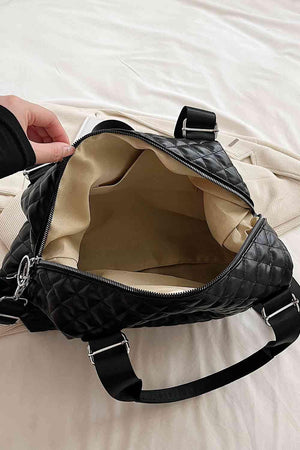 a hand holding a black purse on top of a bed