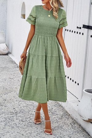 a woman in a green dress walking down a sidewalk