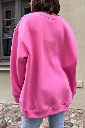 a woman in a pink sweatshirt looking out a window