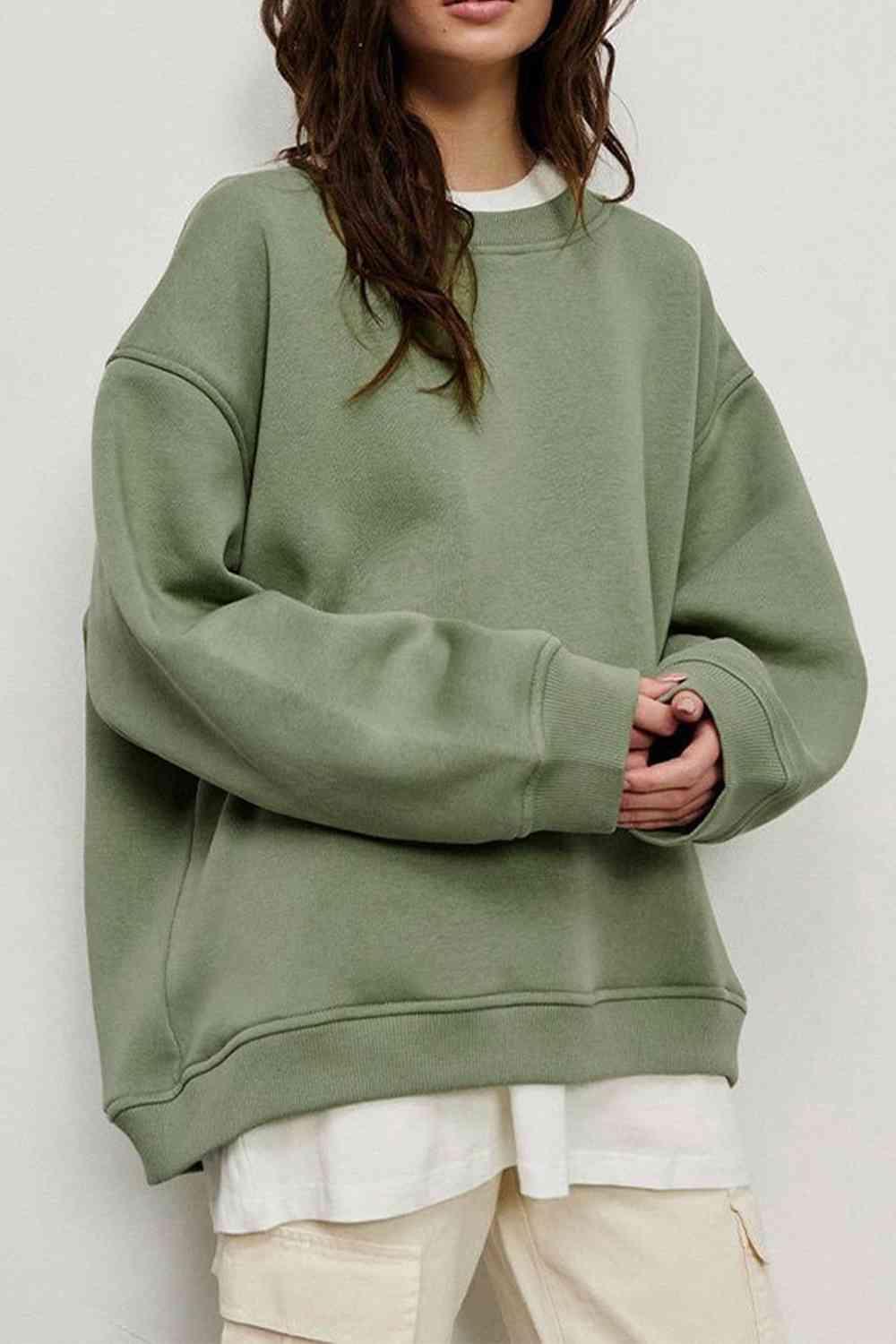 a woman wearing a green sweatshirt and white pants