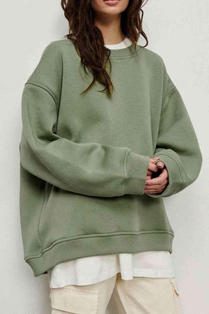 a woman wearing a green sweatshirt and white pants