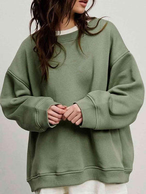 a woman wearing a green sweatshirt and white pants