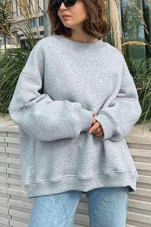 a woman wearing a grey sweatshirt and jeans