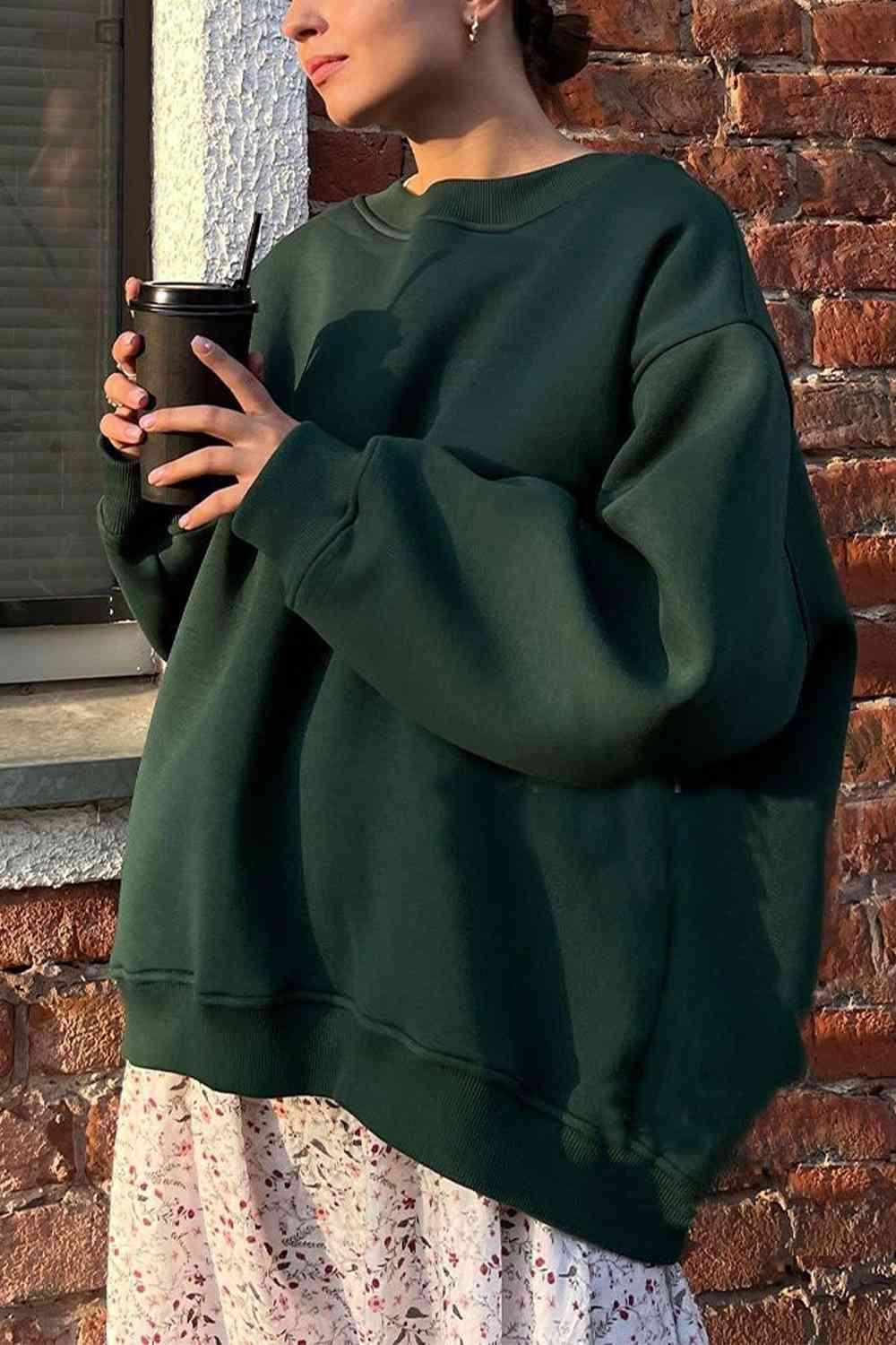 a woman in a green sweatshirt holding a cup of coffee