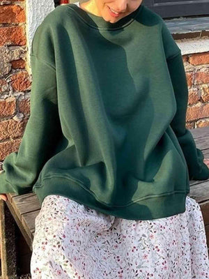 a woman sitting on a bench wearing a green sweatshirt