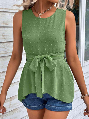 a woman wearing a green top and denim shorts