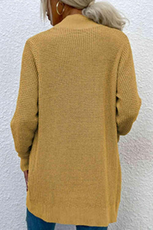 a woman wearing a mustard colored sweater and jeans