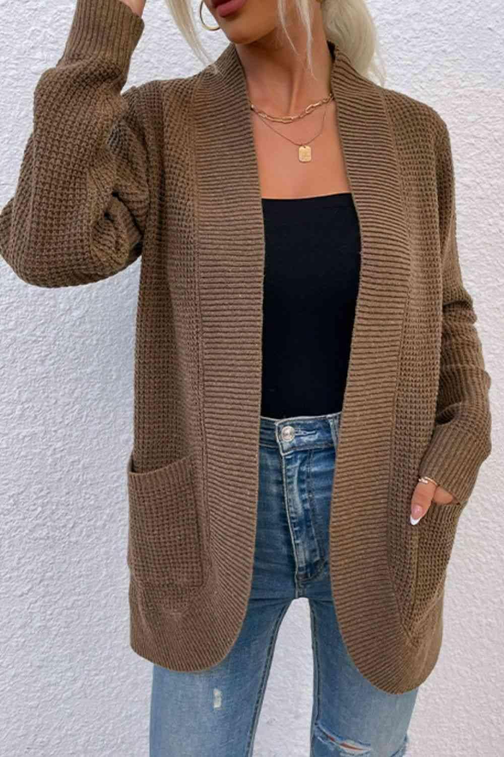 a woman wearing a brown cardigan sweater and ripped jeans