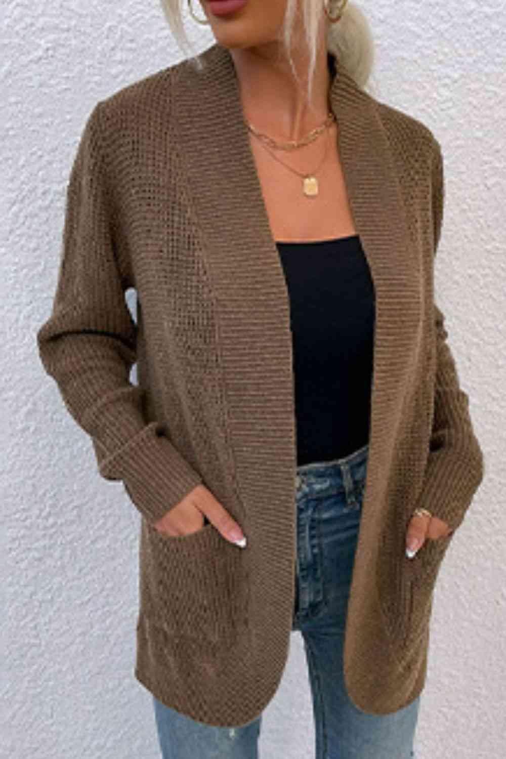 a woman wearing a brown cardigan sweater and jeans