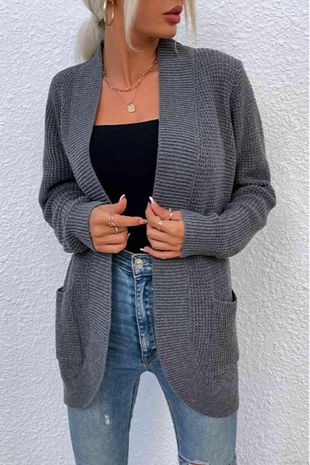a woman wearing a gray cardigan sweater and ripped jeans