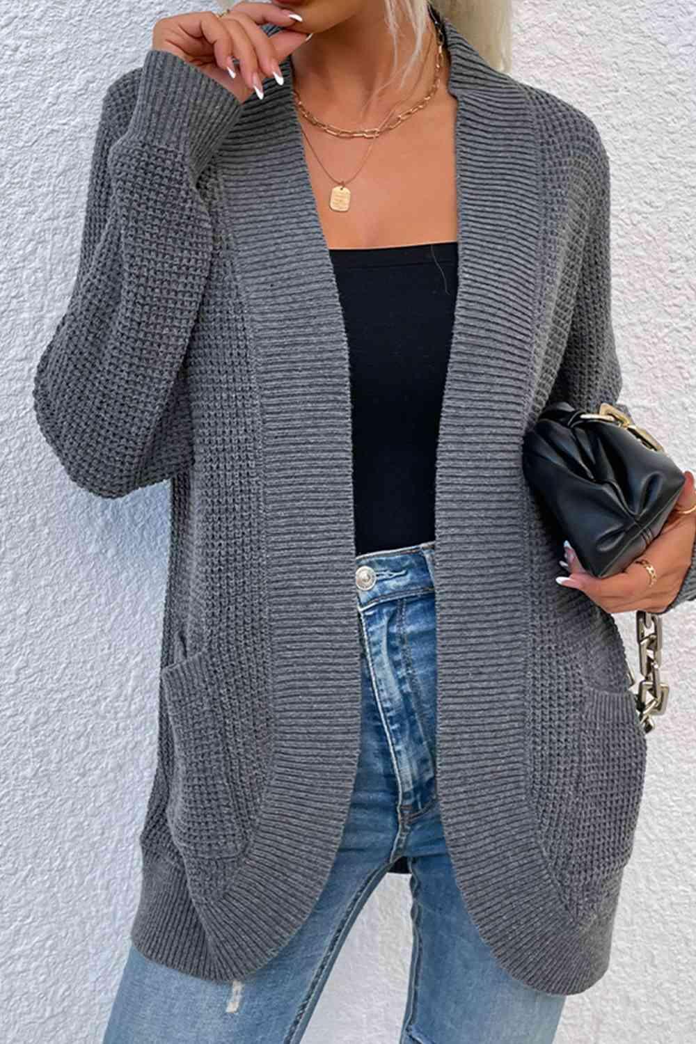 a woman smoking a cigarette while wearing a gray cardigan