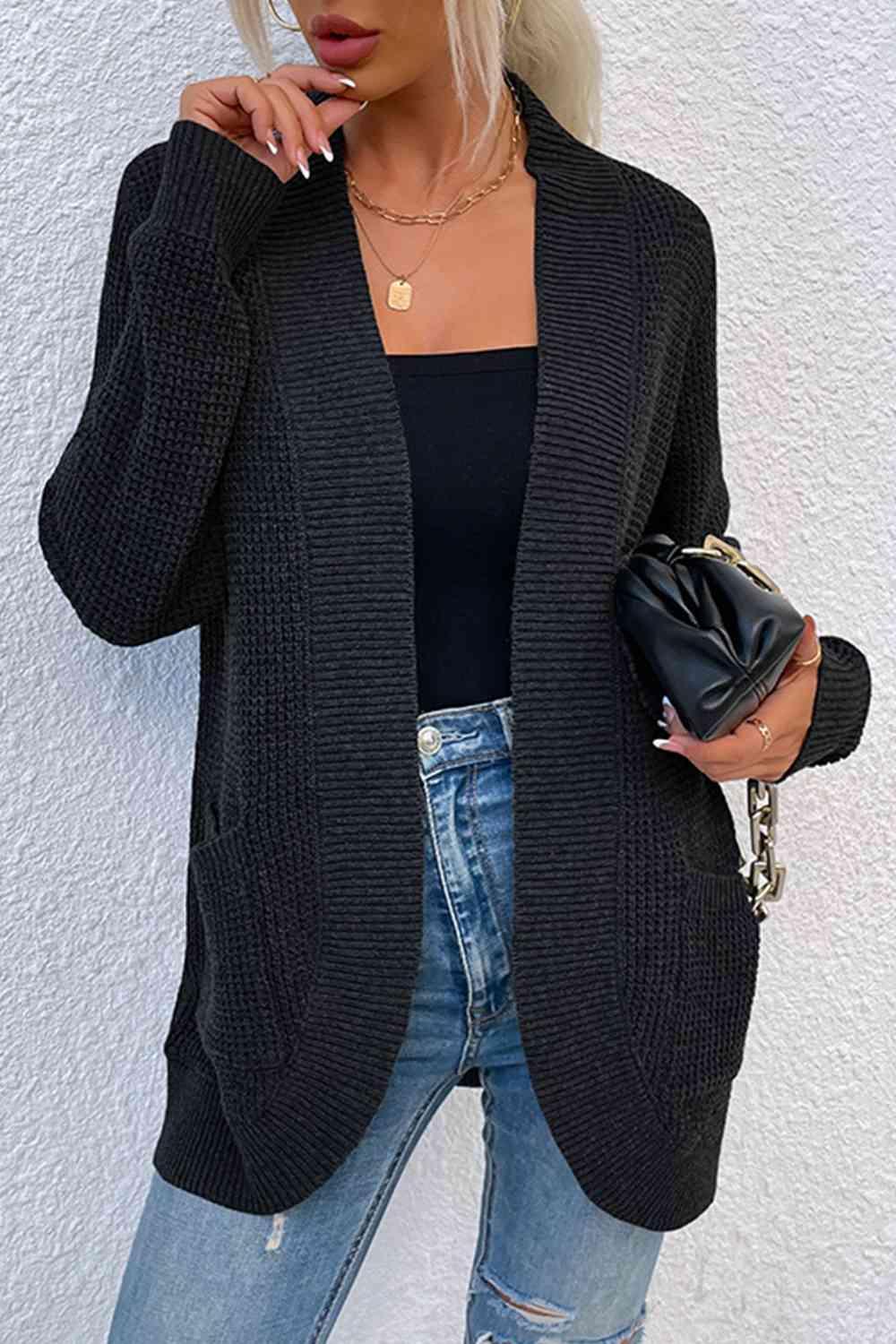 a woman wearing a black cardigan sweater and ripped jeans