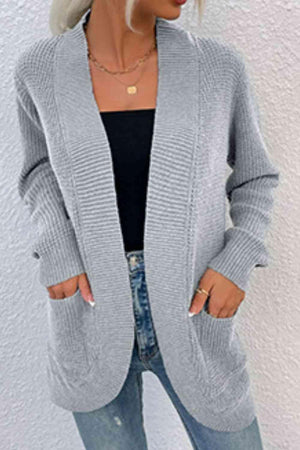 a woman wearing a gray cardigan sweater and jeans