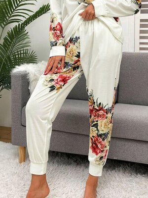 a woman sitting on a couch wearing a white floral jumpsuit