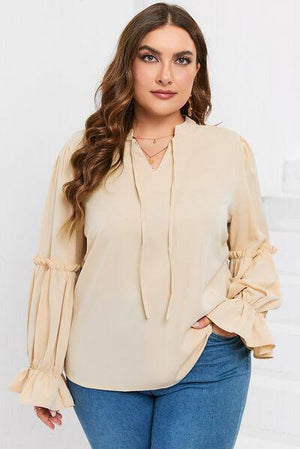 a woman wearing a beige blouse and jeans